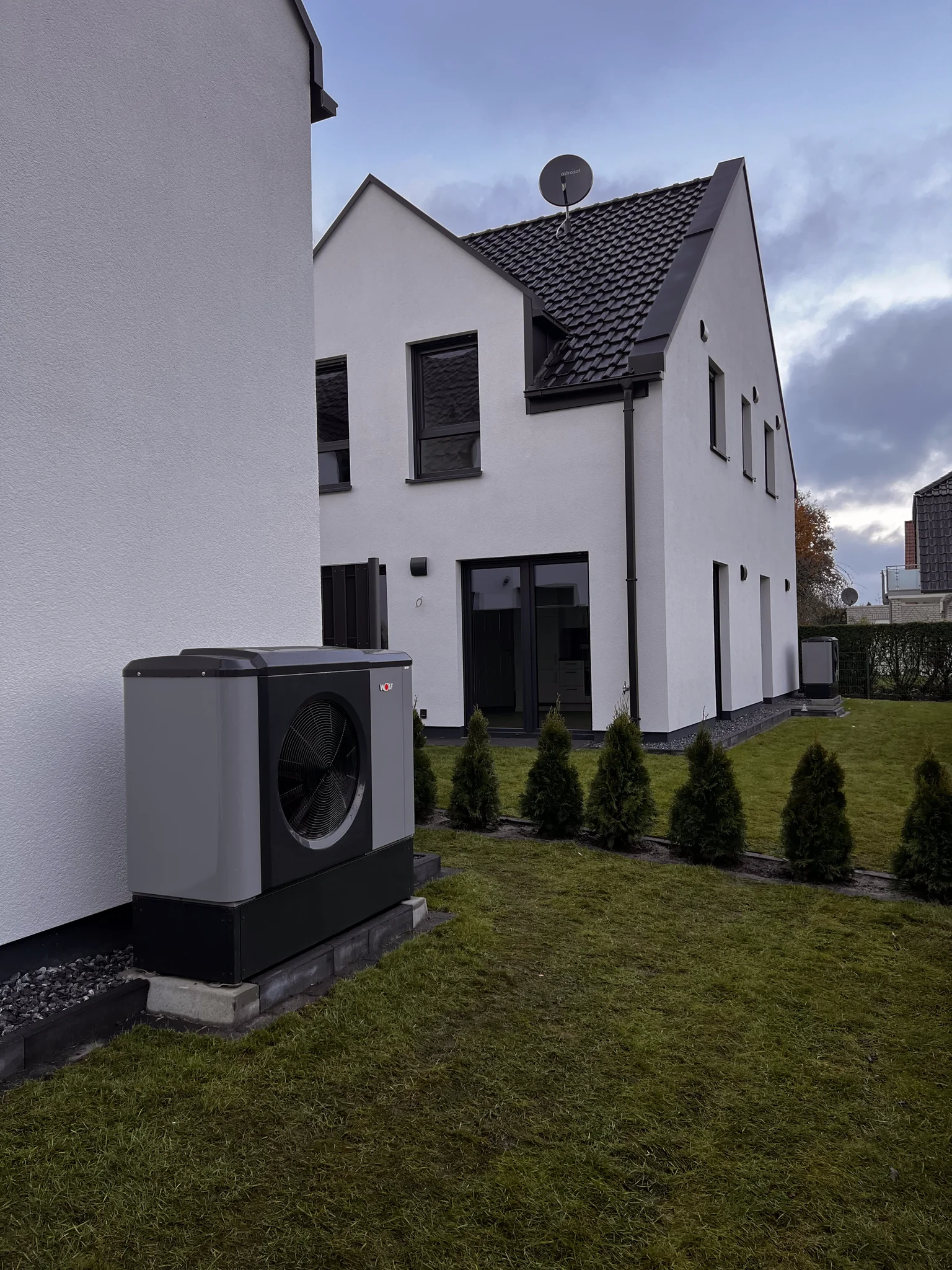 Eine Wärmepumpe aufgestellt auf grünem Rasen vor Gebäuden